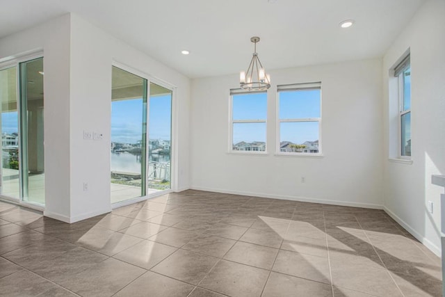 unfurnished dining area featuring tile patterned flooring, a water view, and a notable chandelier