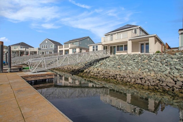 dock area with a water view and a balcony