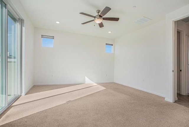 empty room with ceiling fan, light colored carpet, and a healthy amount of sunlight