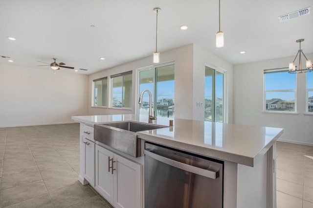 kitchen with dishwasher, ceiling fan with notable chandelier, white cabinets, and a center island with sink