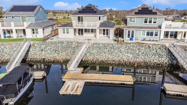 rear view of house featuring solar panels and a water view