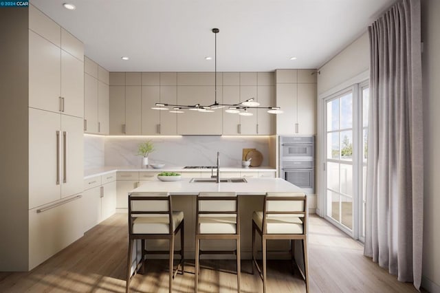 kitchen with light wood-type flooring, a kitchen island with sink, double wall oven, pendant lighting, and a kitchen breakfast bar