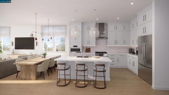 kitchen featuring a kitchen island with sink, appliances with stainless steel finishes, plenty of natural light, and wall chimney range hood