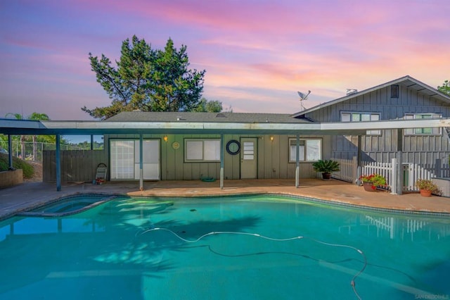 pool at dusk with a patio area