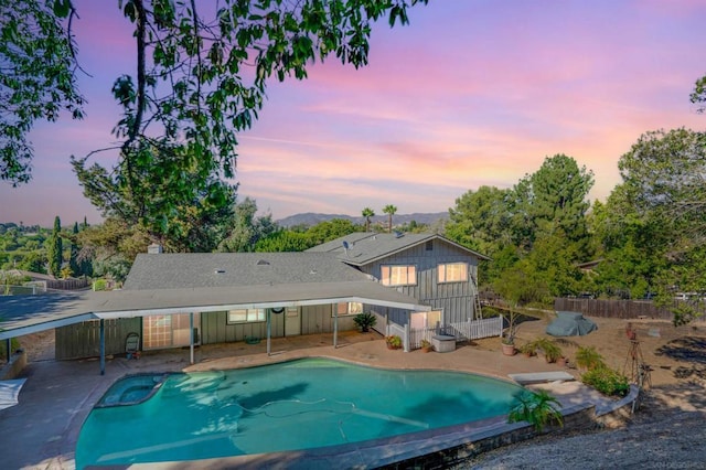 pool at dusk with a patio area