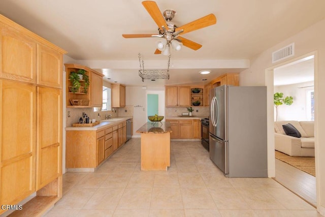 kitchen featuring light tile patterned floors, backsplash, appliances with stainless steel finishes, a center island, and light brown cabinetry