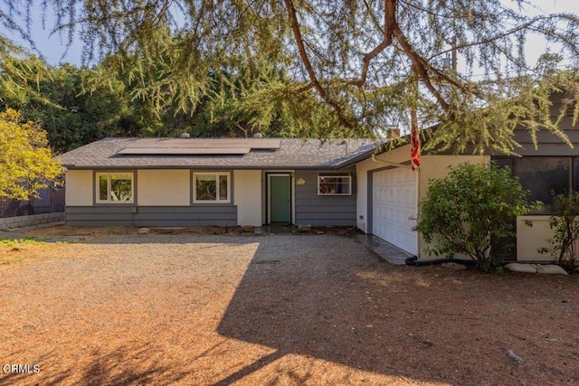 ranch-style home featuring solar panels and a garage