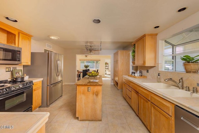 kitchen with a kitchen island, sink, stainless steel appliances, and plenty of natural light