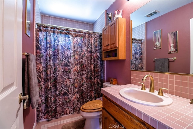 bathroom with tile patterned flooring, tasteful backsplash, a shower with shower curtain, vanity, and toilet