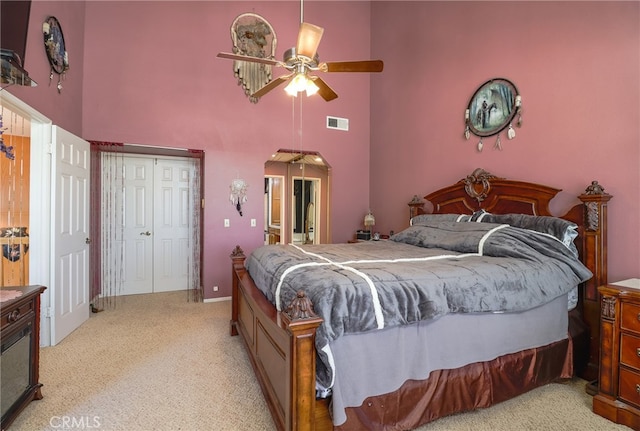 carpeted bedroom featuring ceiling fan and a high ceiling