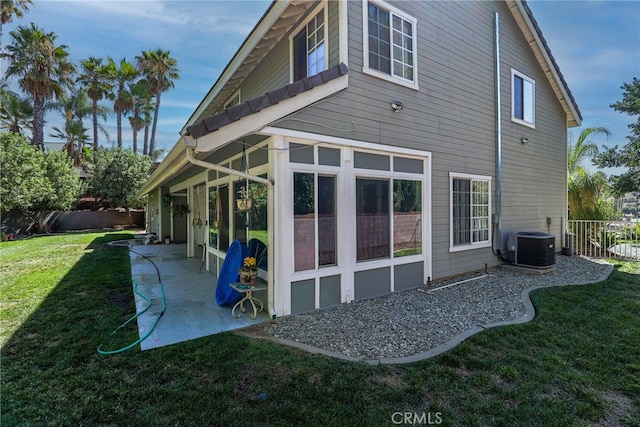 back of house with a sunroom, a patio, central air condition unit, and a yard