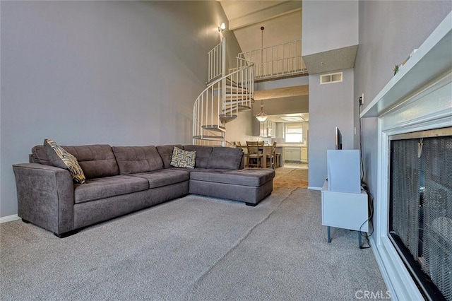 living room featuring visible vents, carpet floors, a towering ceiling, and stairway