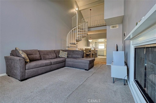 carpeted living area featuring stairs, baseboards, visible vents, and a towering ceiling