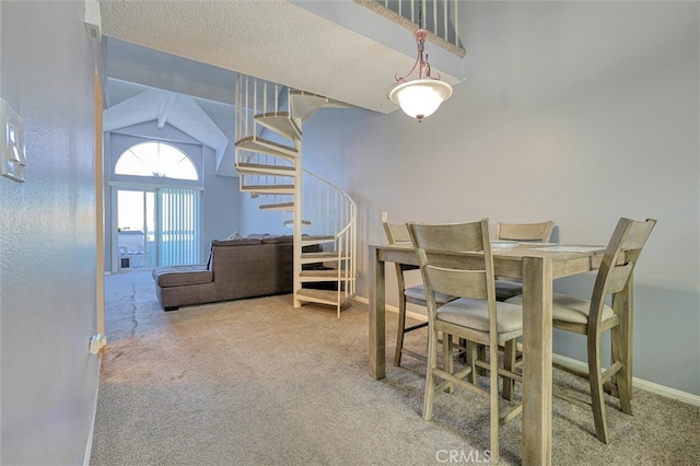 carpeted dining area with vaulted ceiling