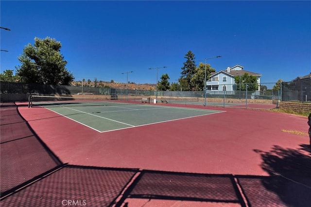 view of tennis court with community basketball court and fence