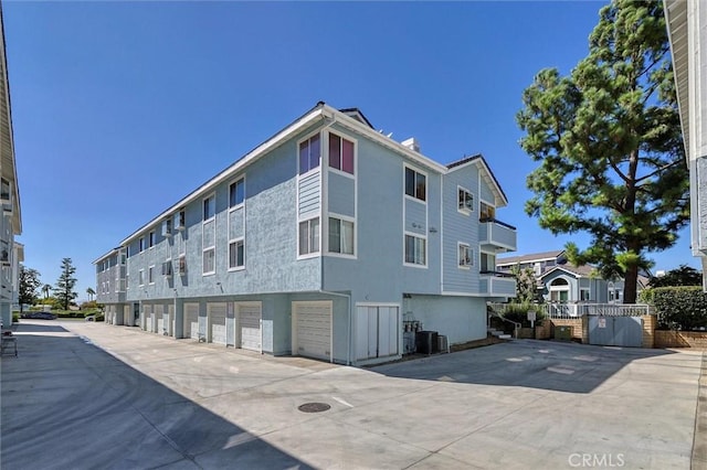 view of property with central air condition unit, driveway, and an attached garage