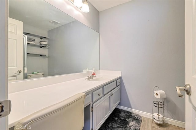 bathroom with visible vents, toilet, wood finished floors, baseboards, and vanity