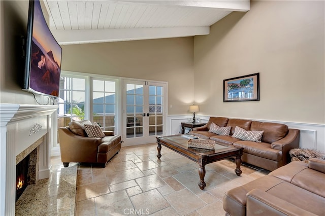 living room with a fireplace, lofted ceiling with beams, and french doors