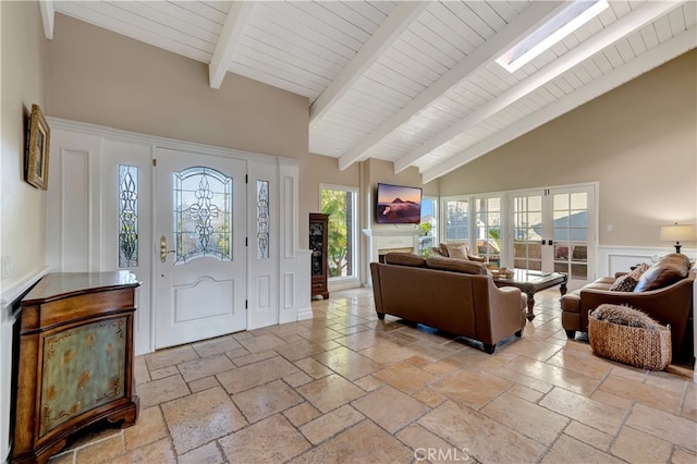 foyer entrance with high vaulted ceiling, a skylight, beamed ceiling, and french doors