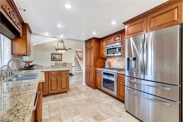 kitchen with pendant lighting, light stone counters, tasteful backsplash, sink, and stainless steel appliances