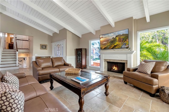 living room with beam ceiling, a wealth of natural light, a high end fireplace, and high vaulted ceiling