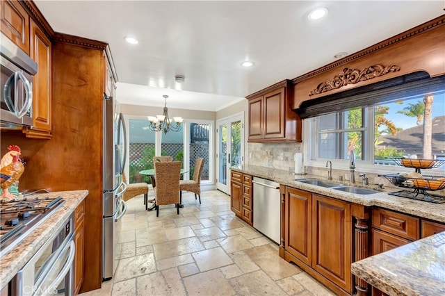 kitchen featuring pendant lighting, tasteful backsplash, sink, an inviting chandelier, and stainless steel appliances