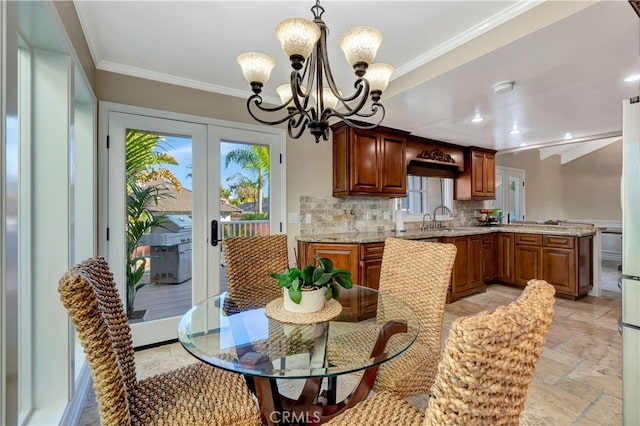 kitchen with hanging light fixtures, decorative backsplash, light stone counters, sink, and a chandelier