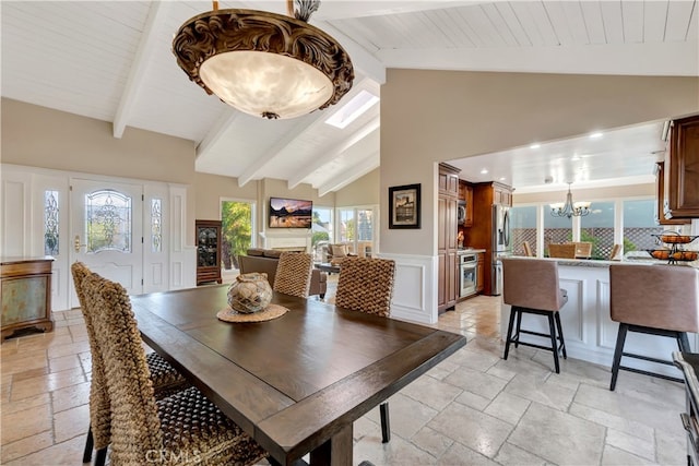 dining space featuring an inviting chandelier, beam ceiling, a skylight, and high vaulted ceiling