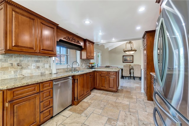 kitchen with tasteful backsplash, sink, kitchen peninsula, stainless steel appliances, and decorative light fixtures