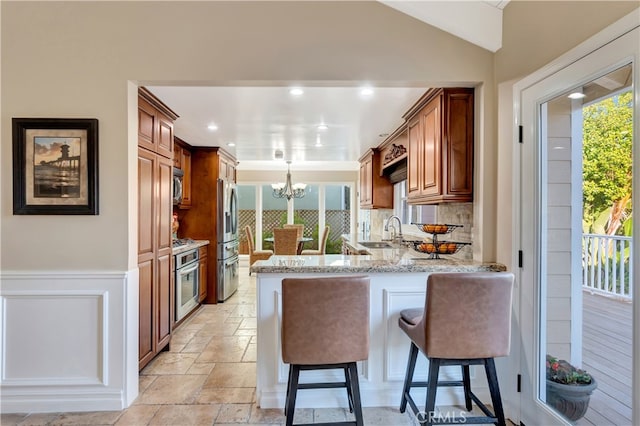 kitchen with kitchen peninsula, a breakfast bar area, stainless steel appliances, sink, and a notable chandelier