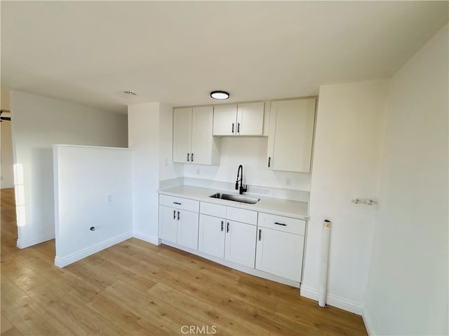 kitchen with white cabinets, light hardwood / wood-style flooring, and sink