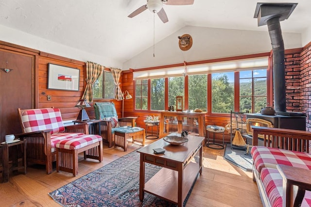 sunroom / solarium featuring ceiling fan, vaulted ceiling, and a wood stove