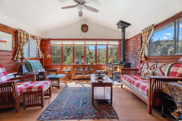 sunroom with vaulted ceiling, ceiling fan, and a wood stove