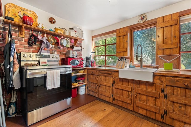 kitchen with stainless steel electric range oven, light hardwood / wood-style flooring, and sink