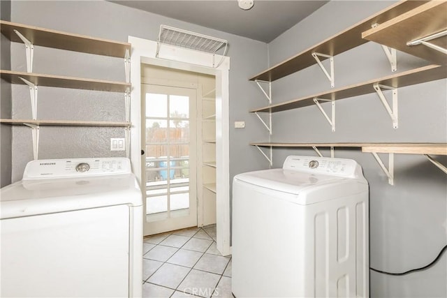 laundry room featuring washing machine and clothes dryer and light tile patterned floors