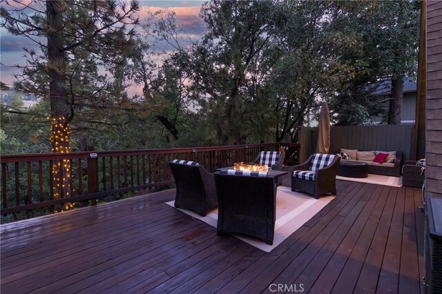 deck at dusk with an outdoor living space with a fire pit