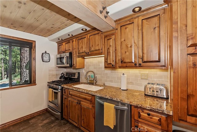 kitchen with brown cabinets, a sink, stainless steel appliances, stone counters, and backsplash