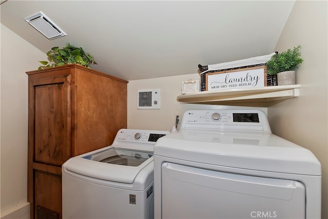 clothes washing area with cabinet space, visible vents, and separate washer and dryer