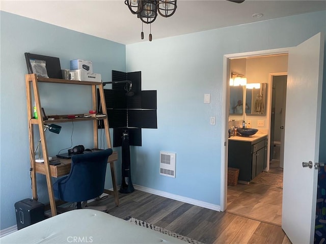 bedroom with heating unit, sink, and light wood-type flooring