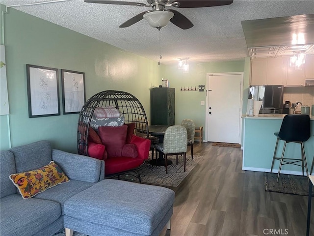 living room featuring ceiling fan, hardwood / wood-style floors, and a textured ceiling