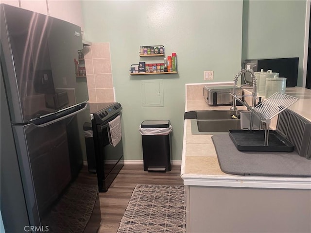 kitchen featuring sink, electric range, wood-type flooring, and stainless steel refrigerator