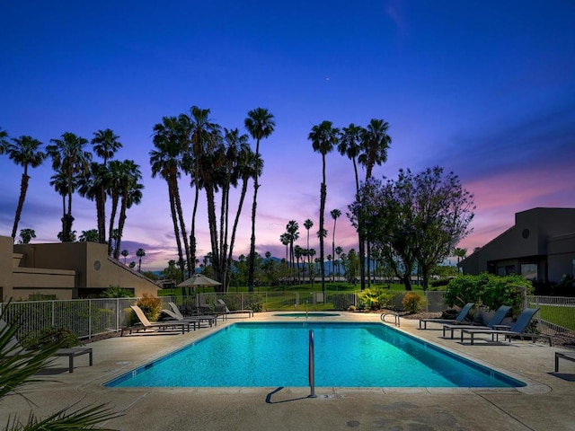 pool at dusk featuring a patio