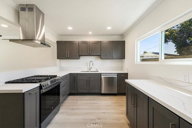 kitchen with light wood-type flooring, sink, island range hood, appliances with stainless steel finishes, and light stone countertops