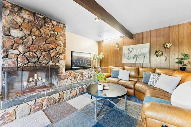 living room with wood walls, beam ceiling, and a stone fireplace