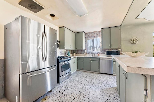 kitchen featuring appliances with stainless steel finishes, kitchen peninsula, decorative backsplash, and sink