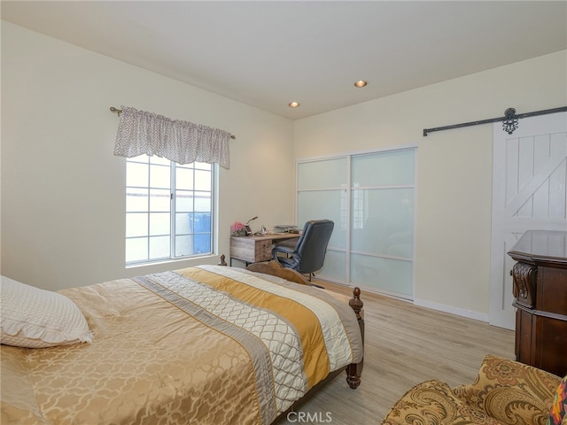 bedroom featuring light hardwood / wood-style floors and a barn door