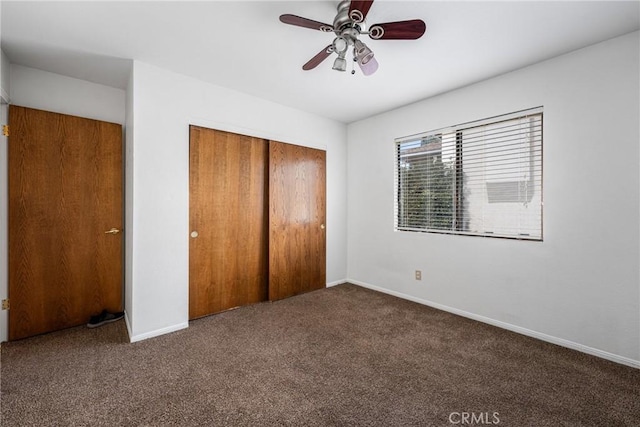 unfurnished bedroom featuring dark colored carpet, a closet, and ceiling fan