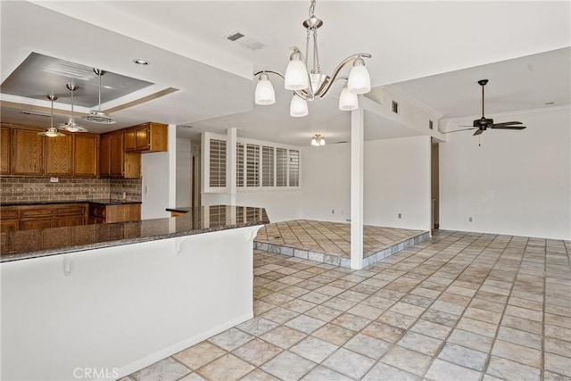 kitchen featuring a kitchen breakfast bar, ceiling fan with notable chandelier, tasteful backsplash, and hanging light fixtures