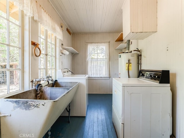 clothes washing area featuring water heater, dark hardwood / wood-style floors, washer and dryer, and sink