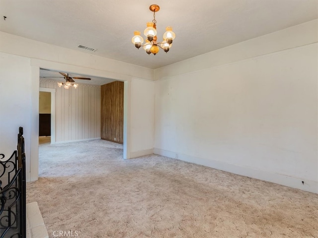 empty room featuring ceiling fan with notable chandelier and carpet